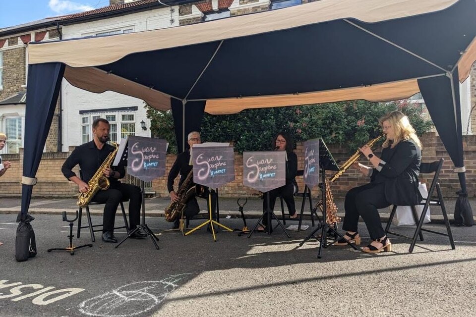 All four members of Swan Saxophone Quartet performing under an outdoor canopy