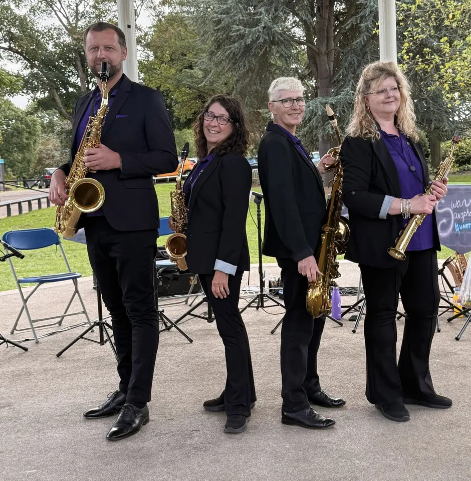 The four members of Swan Saxophone Quartet holding their saxophones at an outdoor bandstand